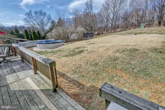 view of yard featuring a covered pool, a trampoline, and a wooden deck