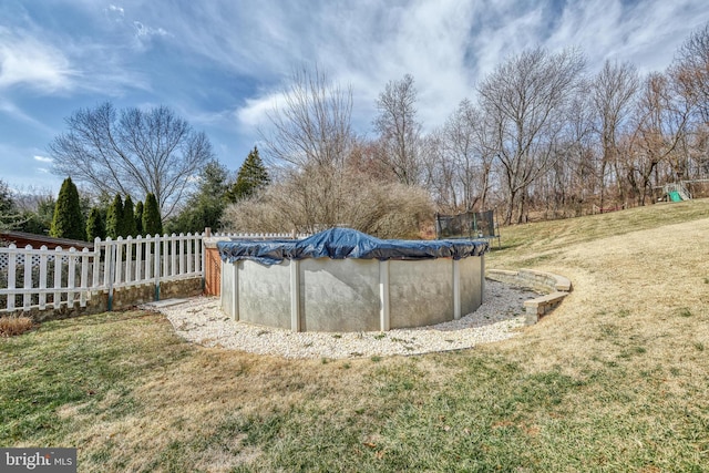 view of pool with a covered pool, fence, and a yard