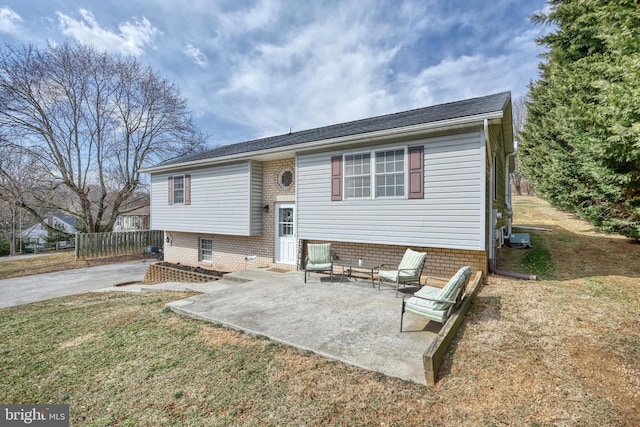 raised ranch featuring entry steps, a patio, and a front lawn