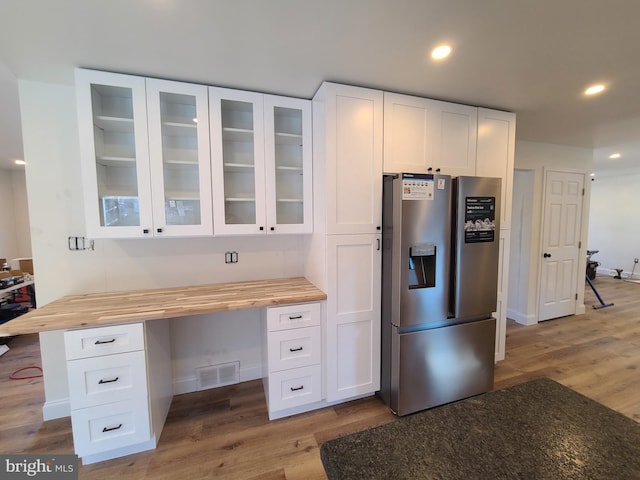 kitchen featuring white cabinets, stainless steel fridge with ice dispenser, and wooden counters