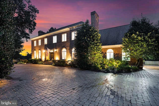 view of front of home featuring brick siding and a chimney