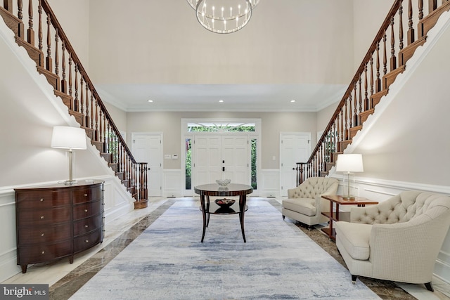 living area with a towering ceiling, stairs, and ornamental molding