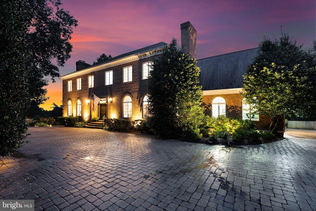 view of front of home with brick siding and a chimney