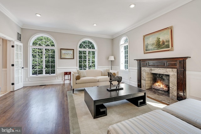 living area featuring a wainscoted wall, crown molding, a premium fireplace, and wood finished floors