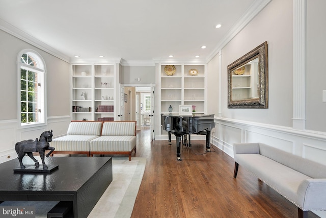 living area with built in features, a wainscoted wall, crown molding, and wood finished floors