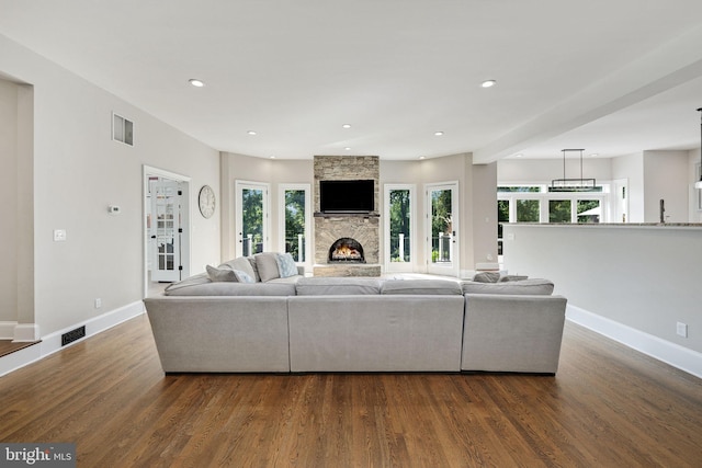 living room with baseboards, visible vents, dark wood-type flooring, a fireplace, and recessed lighting