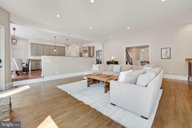 living area featuring baseboards, stairway, wood finished floors, and recessed lighting