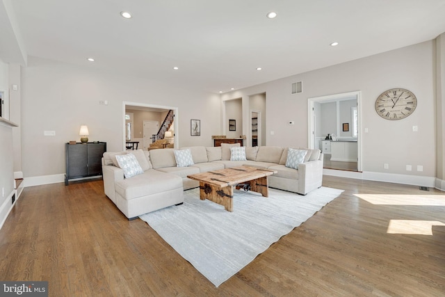 living area with recessed lighting, visible vents, stairway, light wood-style flooring, and baseboards