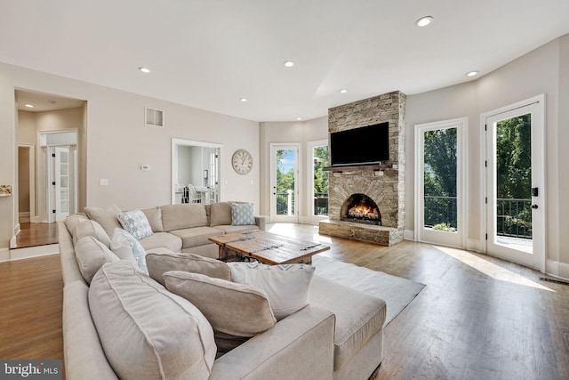 living room featuring a fireplace, recessed lighting, visible vents, wood finished floors, and baseboards