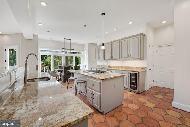 kitchen with beverage cooler, a kitchen island, a sink, and gray cabinetry