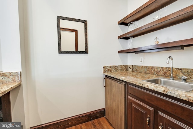 kitchen with dark wood finished floors, open shelves, a sink, dishwasher, and baseboards