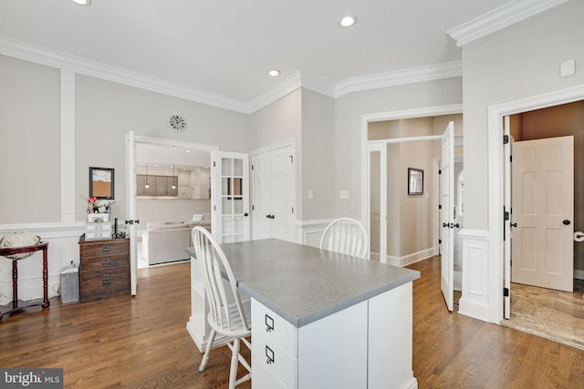 kitchen with recessed lighting, dark wood-style flooring, a kitchen island, a kitchen breakfast bar, and ornamental molding