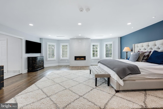 bedroom featuring baseboards, a fireplace, wood finished floors, and recessed lighting