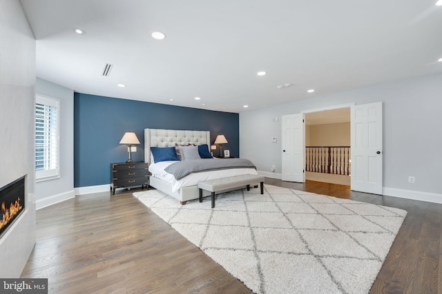 bedroom featuring baseboards, a fireplace, wood finished floors, and recessed lighting