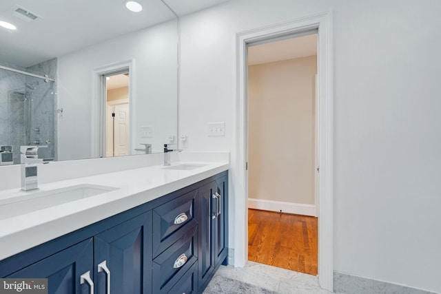 bathroom with double vanity, a stall shower, a sink, and visible vents