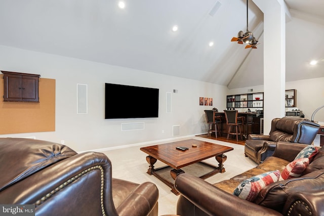 living room with a ceiling fan, light carpet, a bar, high vaulted ceiling, and baseboards