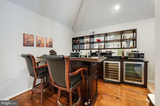 bar with vaulted ceiling, wine cooler, stainless steel microwave, and wet bar