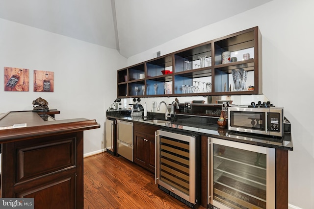 bar with beverage cooler, wet bar, stainless steel microwave, and a sink