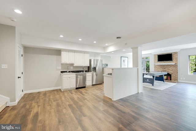 kitchen featuring light wood finished floors, stainless steel appliances, a sink, and open floor plan