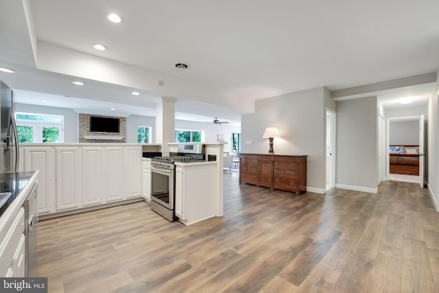 kitchen featuring stainless steel gas range oven, visible vents, white cabinetry, open floor plan, and light wood-type flooring