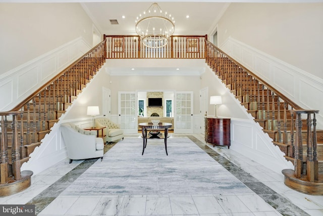 living room featuring a chandelier, marble finish floor, ornamental molding, and a decorative wall