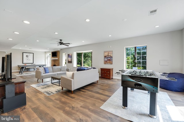 living room with baseboards, visible vents, wood finished floors, a fireplace, and recessed lighting