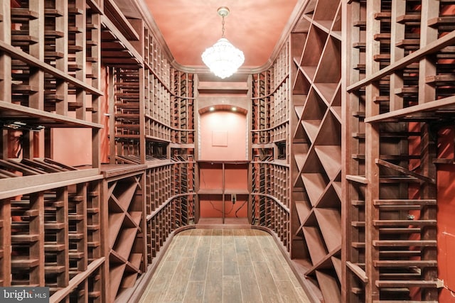 wine area featuring an inviting chandelier and wood finished floors