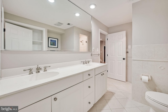 bathroom with a sink, tile walls, toilet, and tile patterned floors