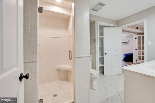 bathroom with visible vents, toilet, a stall shower, vanity, and tile patterned flooring