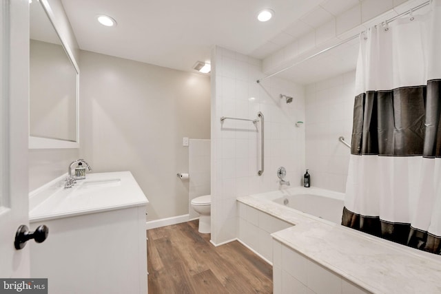 full bath featuring baseboards, toilet, wood finished floors, tiled shower / bath combo, and vanity