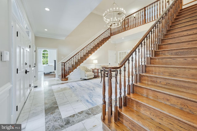 entrance foyer featuring marble finish floor, a notable chandelier, crown molding, recessed lighting, and stairs