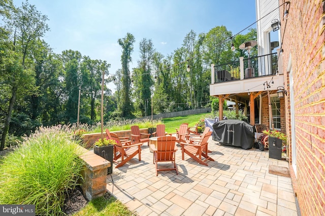 view of patio / terrace with a balcony, a fire pit, fence, and area for grilling