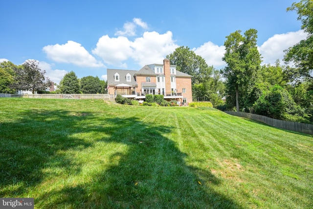 rear view of property with fence, a chimney, a wooden deck, and a lawn