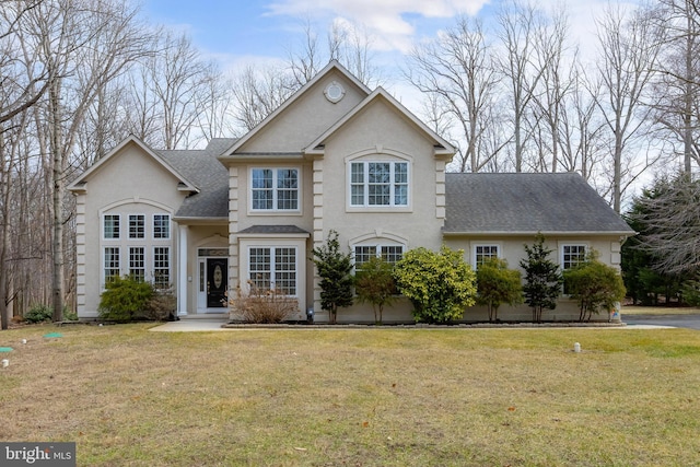 view of front of house featuring roof with shingles, a front lawn, and stucco siding