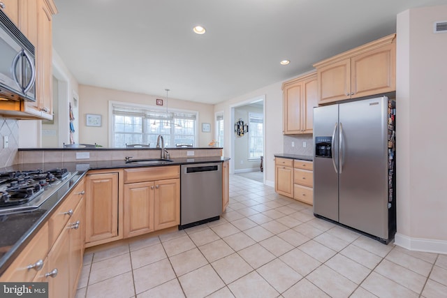 kitchen with tasteful backsplash, light brown cabinets, stainless steel appliances, and a sink