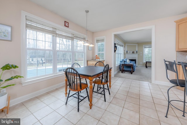 dining room with light tile patterned floors, plenty of natural light, a fireplace, and baseboards