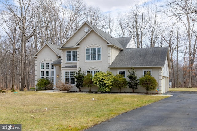 view of front of property with a garage, a front lawn, a shingled roof, and stucco siding