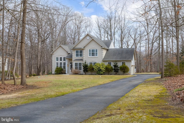 view of front facade featuring a shingled roof, a front lawn, and stucco siding