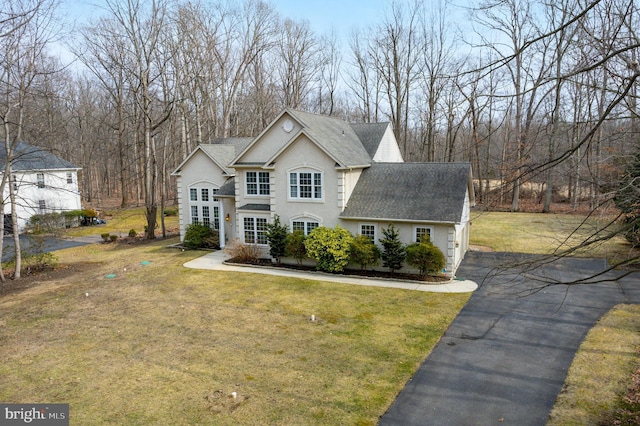 view of front of property featuring a front yard, roof with shingles, driveway, and stucco siding