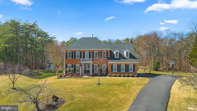 view of front facade featuring a front yard, brick siding, and driveway