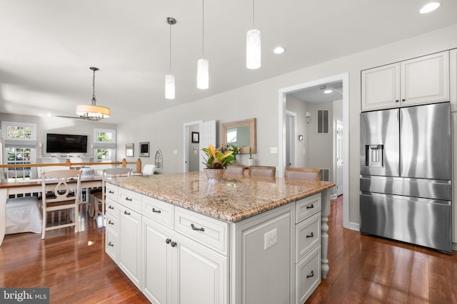 kitchen featuring decorative light fixtures, light stone countertops, dark wood-type flooring, and stainless steel fridge with ice dispenser