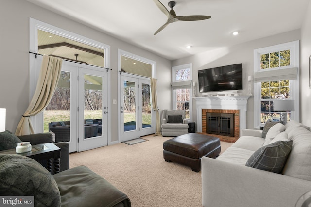 carpeted living room with a brick fireplace, recessed lighting, a ceiling fan, and french doors