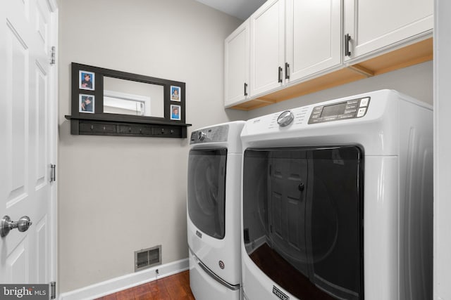 laundry area with washing machine and clothes dryer, visible vents, baseboards, dark wood finished floors, and cabinet space