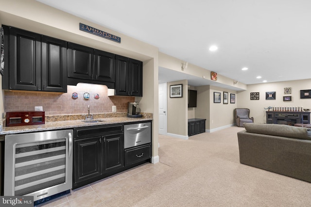 kitchen with a warming drawer, wine cooler, dark cabinets, and a sink