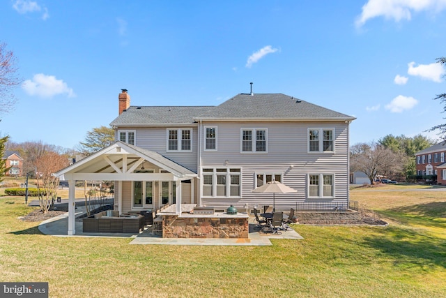 rear view of property with a lawn, a shingled roof, an outdoor hangout area, a chimney, and a patio area