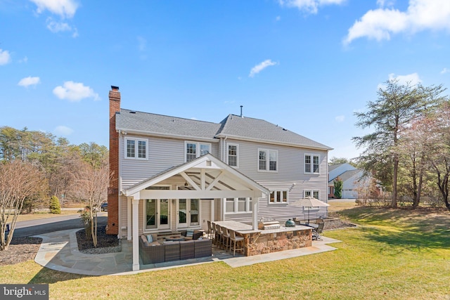 back of property featuring an outdoor living space, exterior kitchen, a lawn, a chimney, and a patio