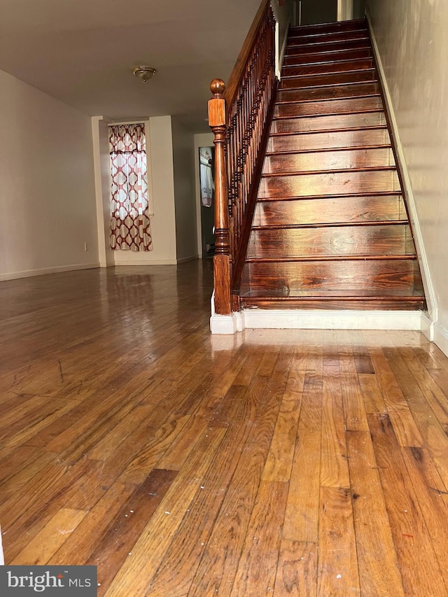 stairway featuring wood-type flooring and baseboards