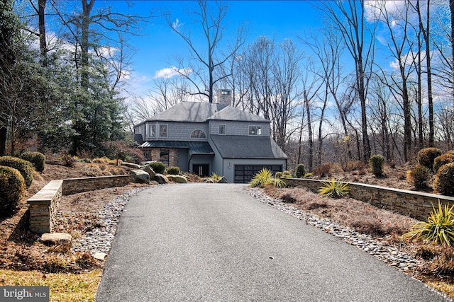 view of front of property with driveway, an attached garage, a standing seam roof, and metal roof