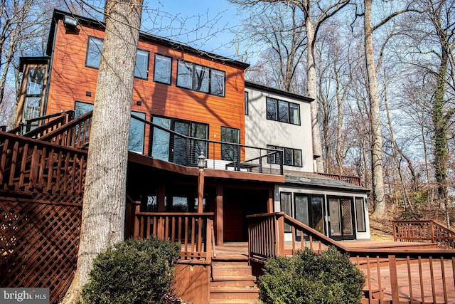 back of house with a deck, a balcony, and a sunroom