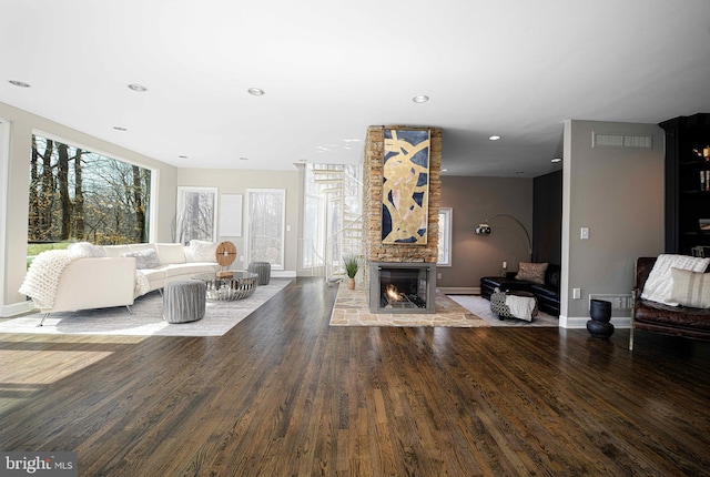 living area featuring a fireplace, wood finished floors, visible vents, and baseboards